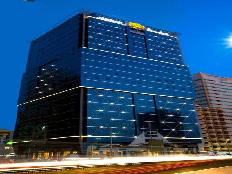 Hotel Jannah Burj Al Sarab Abu Dhabi Esterno foto The photo shows a modern skyscraper with a sleek, glass facade, reflecting a night sky. The building is illuminated with bright lights, making it stand out against the evening backdrop. The structure has multiple floors and appears to be part of a co